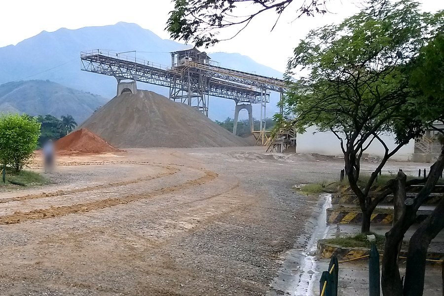 Planta industrial en Yumbo con banda transportadora, acopio de material y la cordillera al fondo